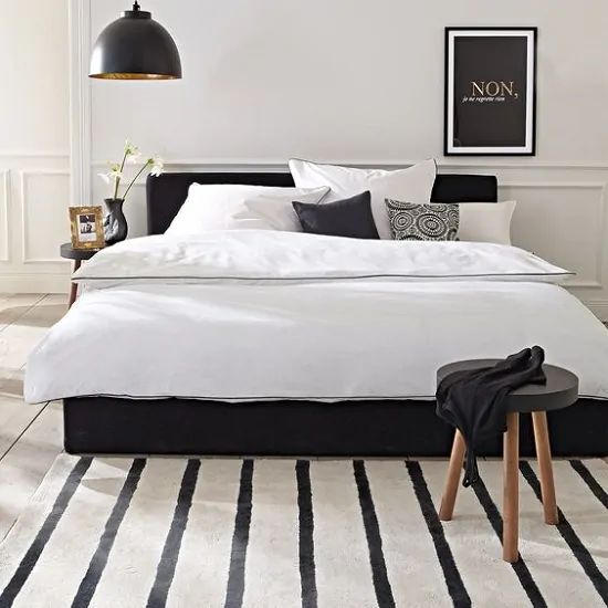 Ideia simples para decorar um quarto preto e branco com tapete listrado e cama preta