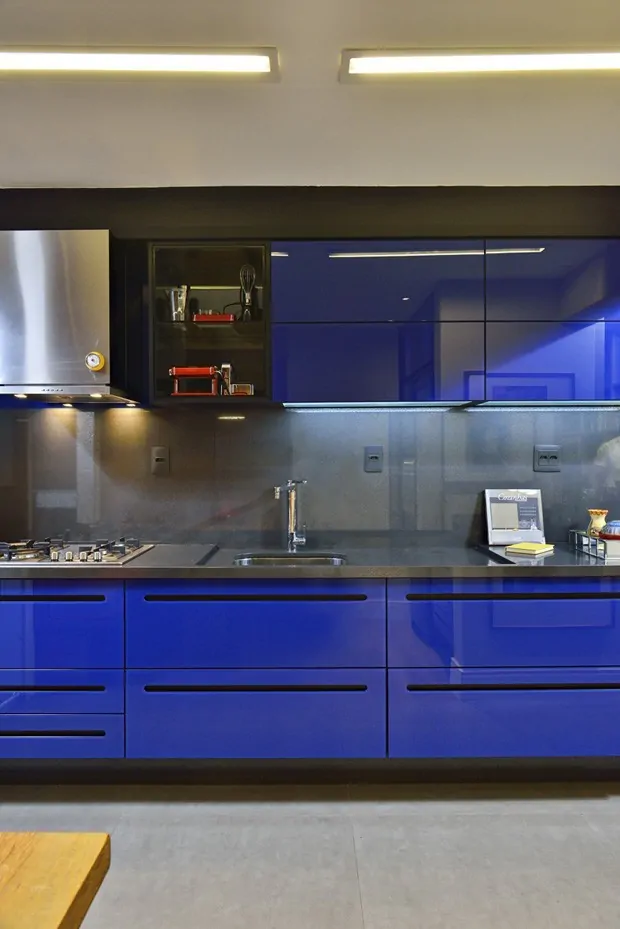 Móveis azul escuro brilhosos na cozinha com tampo cinza