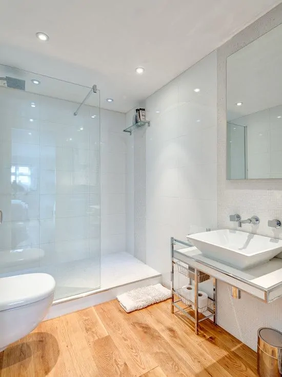 Banheiro simples branco com piso de madeira