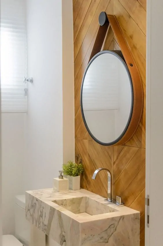 Espelho com alça de couro e parede de madeira no lavabo pequeno