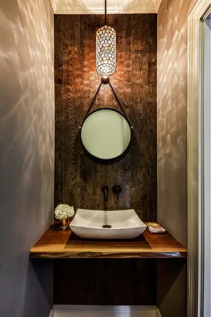 Decoração de lavabo pequeno com espelho com alça e parede revestida de porcelanato que imita madeira