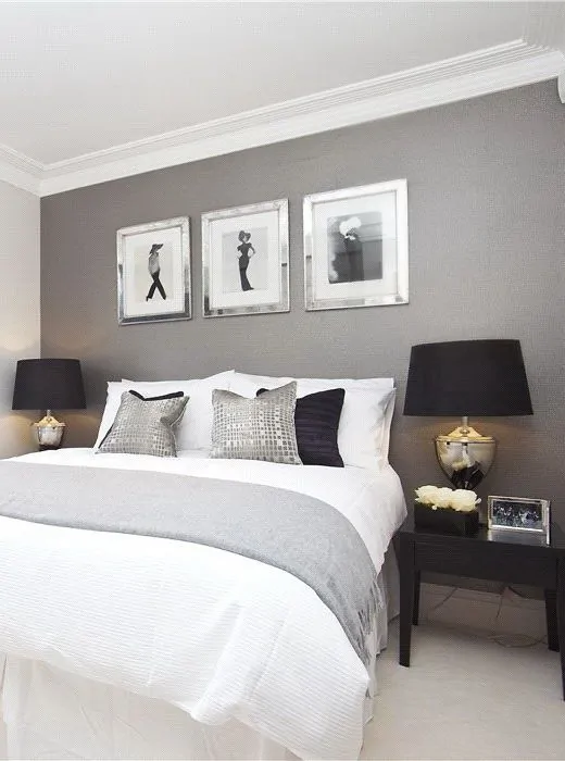 Dormitório elegante, com quadros e parede pintada de cinza