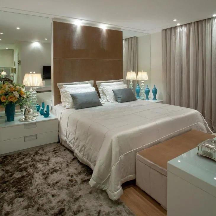 Decoração elegante com cama estofada, abajur elegantes e espelhos nas laterais da cama