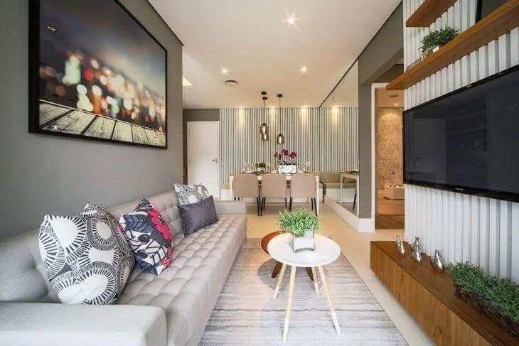 Sala moderna em apartamento pequeno, com espelho no jantar e painel para TV ripado